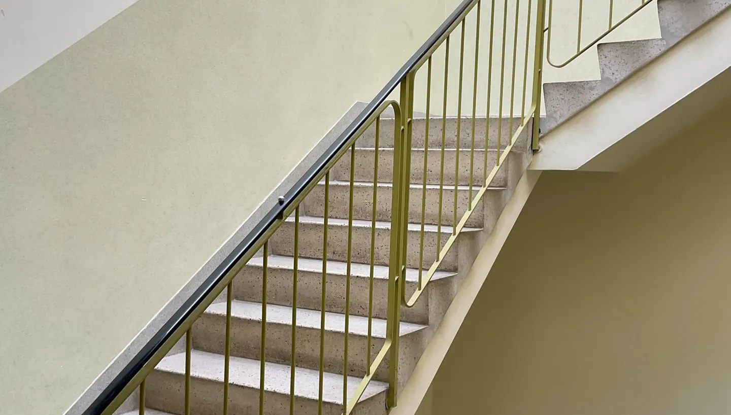 Stiegenhaus eines Wohnhauses mit Geländer und Handlauf.