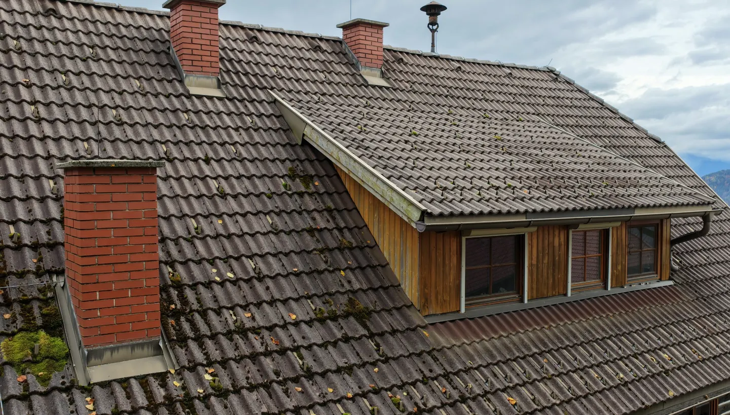 Ziegelgedecktes Steildach mit Gaube und Kamin aus der Luft.