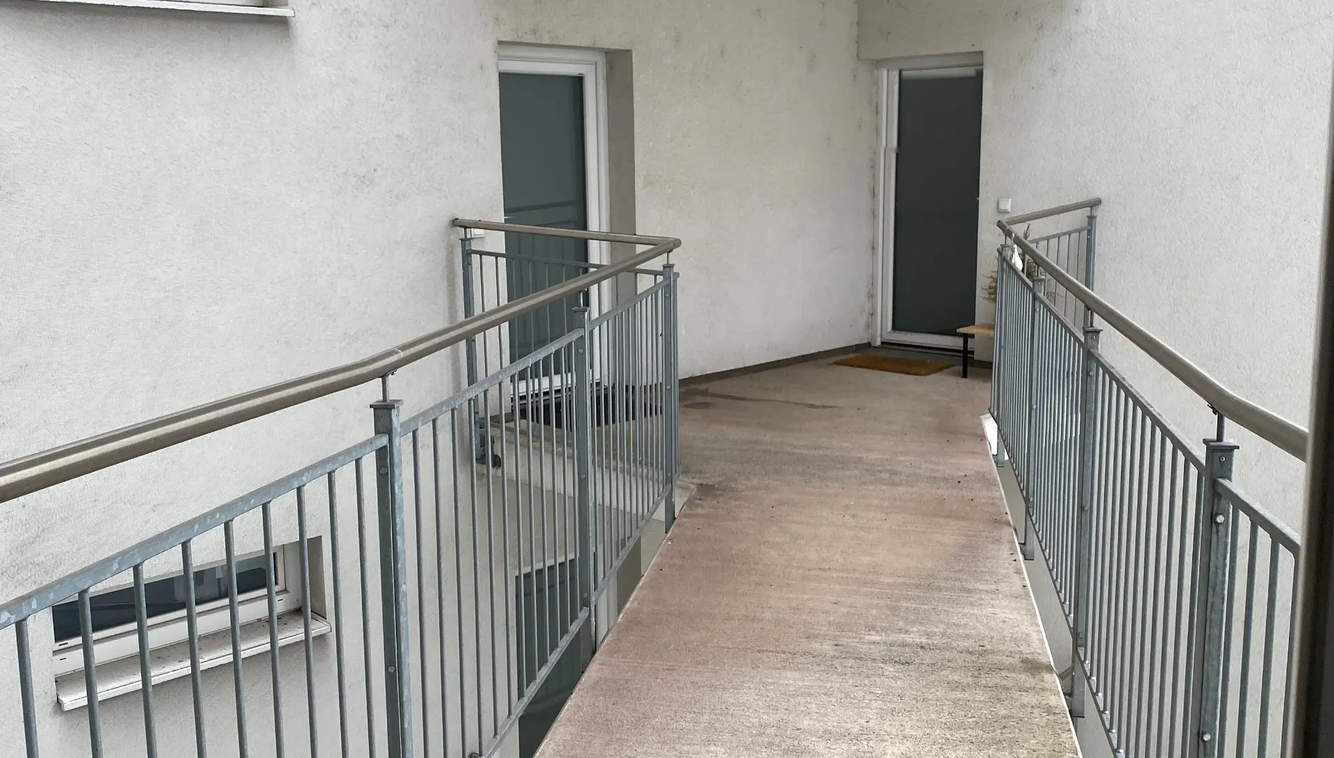 Laubengang mit Geländern in einem Wohnhaus.