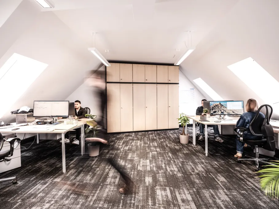 Das Themis Büro: Mitarbeitende bearbeiten Gebäudeunterlagen an ihren Arbeitsplätzen.