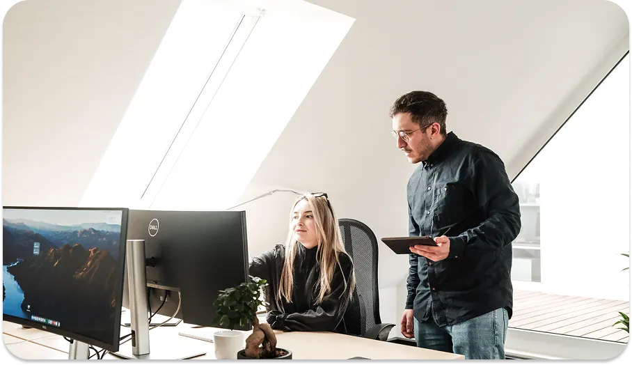 Zwei Themis Mitarbeitende prüfen Planunterlagen am Bildschirm im Büro.