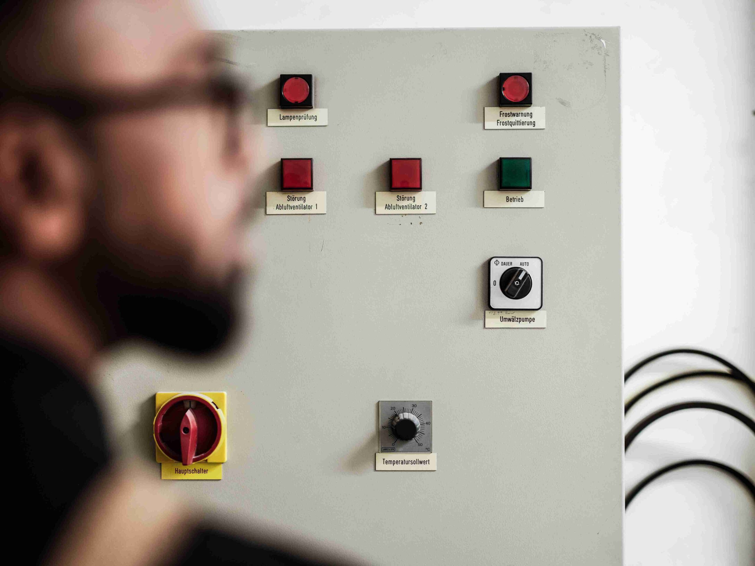 Ein Prüfingenieur von Themis kontrolliert die Steuerungsschalter und Warnleuchten einer haustechnischen Anlage im Rahmen einer Objektsicherheitsprüfung.